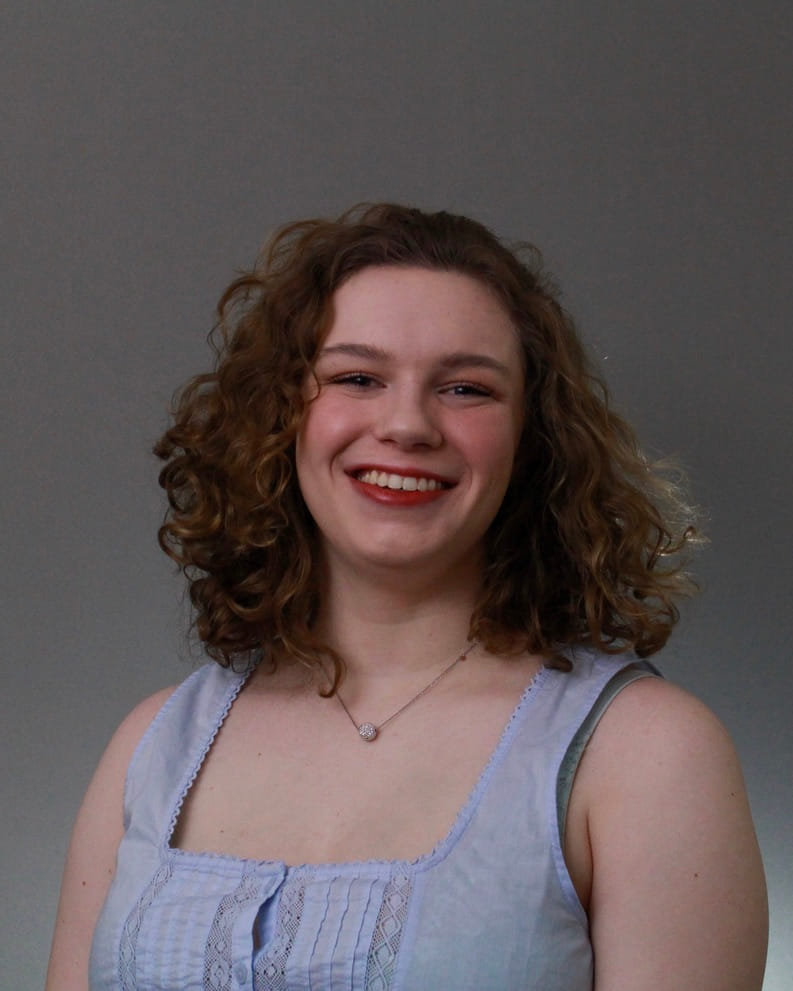 Hannah's headshot. She smiles at the camera, posed in front of a gray backdrop.