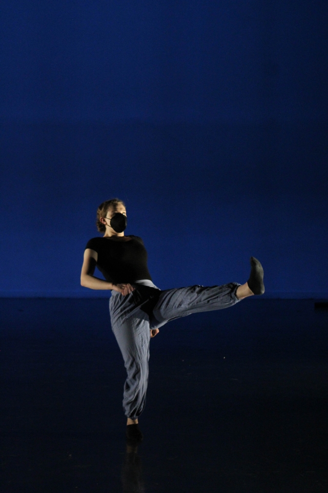 Hannah faces the camera, looking out to the distance. She has one leg extended in front of her with the foot flexed.