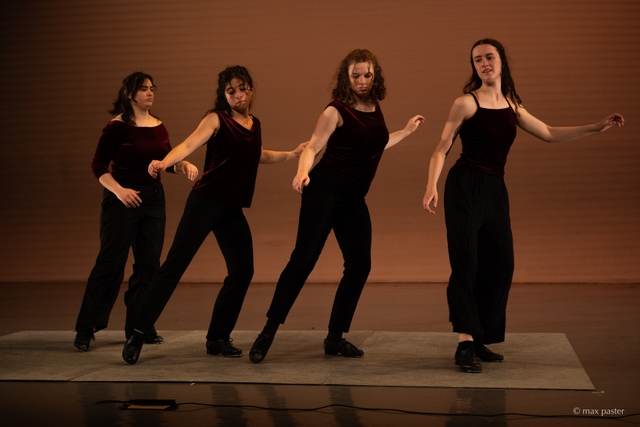 Hannah (second from the right) dances with her foot extended towards the front, and her arms out to her sides. The other three dancers mirror her position.